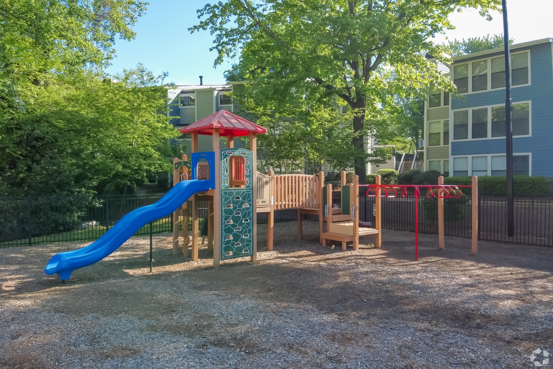A playground with a blue slide and a red roof.